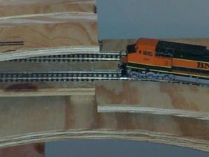 orange model train on section of a helix railroad