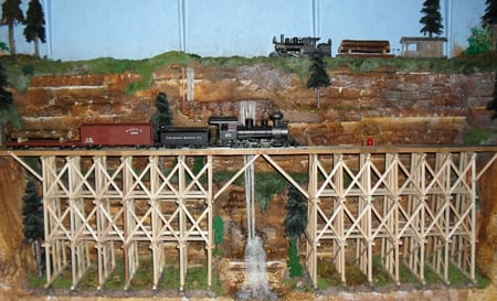 model train crossing a bridge next to waterfall