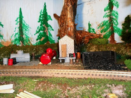 equipment on the side of the model tracks with backdrop of trees