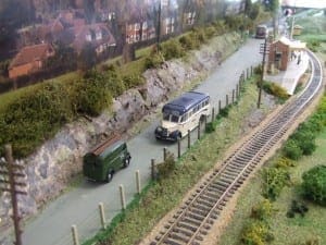 Truck and van driving along the road beside the train track. 