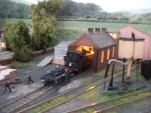 Model train emerging from a garage. 