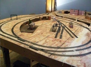 Miniature houses and model train tracks on a wooden table.