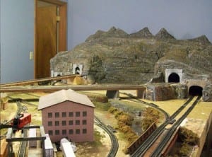 Three tunnels, a house, and mountains on the model railroad.