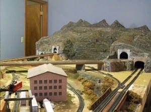 Three tunnels, a house, and mountains on the model railroad.