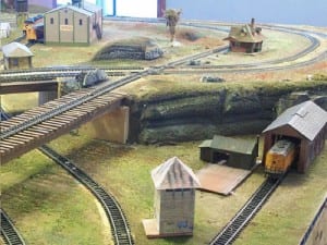Model train inside garage beside train tracks on separate levels.