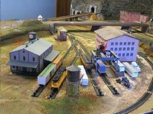 Model trains and trucks in between two buildings.