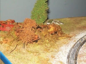 Rusted engine by a tree on the model railroad layout.