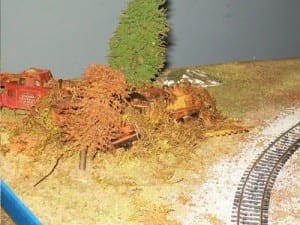 Rusted engine by a tree on the model railroad layout.