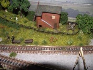 Farm by the side of the railroad with background scenery.