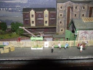 People waiting for the model train on the platform with a crane behind them. 