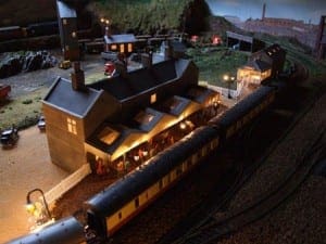 People at a house during the night time on the model railroad.