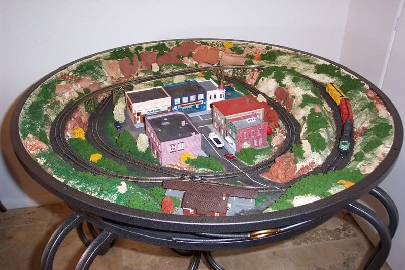 Circular coffee table with model train layout on top. 