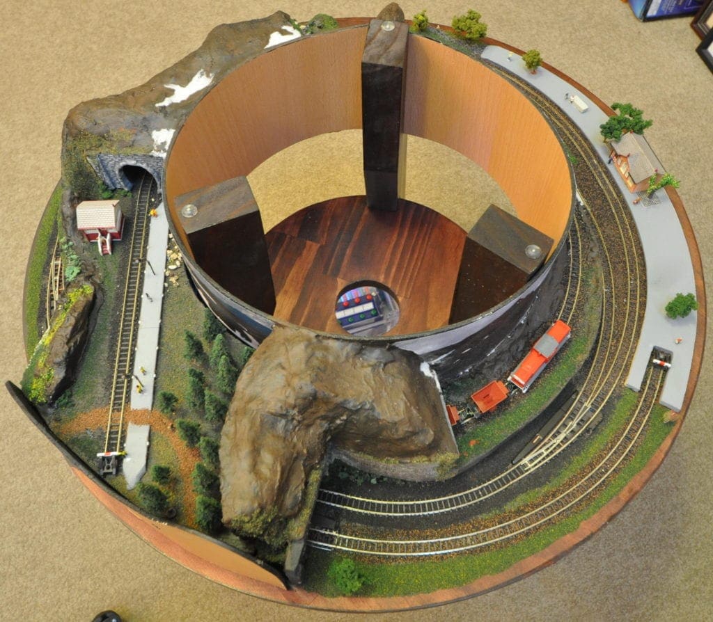 Z scale train layout the size of a coffee table with a cylindrical backdrop in the middle