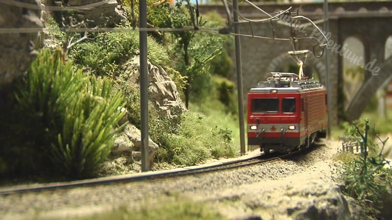 a model train is crossing a tunnel under a mountain