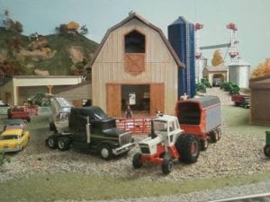 farmhouse with trucks and tractors of model railroad