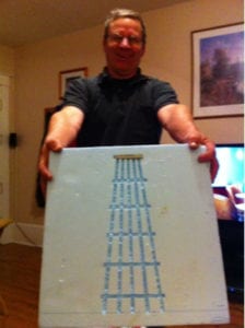 man holding canvas with print of bridge support for model railroad