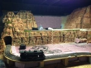 model train moving across the tracks near the mountain tunnel entrance