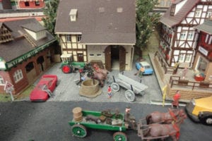 Cars and horse-drawn carriages in the model railroad town.