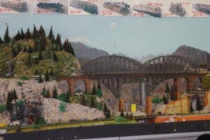 Hill with pine trees and the side of the bridge on the model railroad.