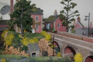 red buildings and a bridge under grey skies of the model railroad layout
