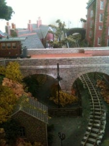 carriage on top of a bridge and houses on the model railroad layout
