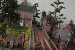model train tracks running between red buildings