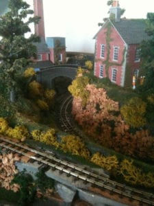 Red house near two model train tracks