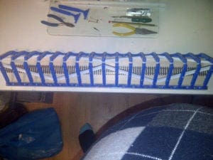 model train track under blue and white bridge brace with tools