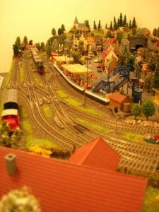 Train approaching a curve on the track by a house. 