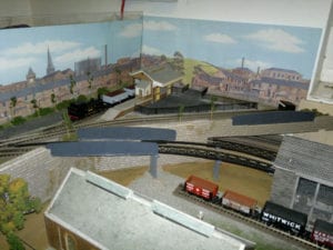backdrop of houses and buildings of a model railroad