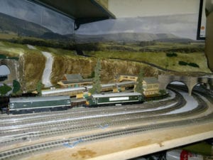 tunnel, train station, and train models sitting on tracks of model railroad