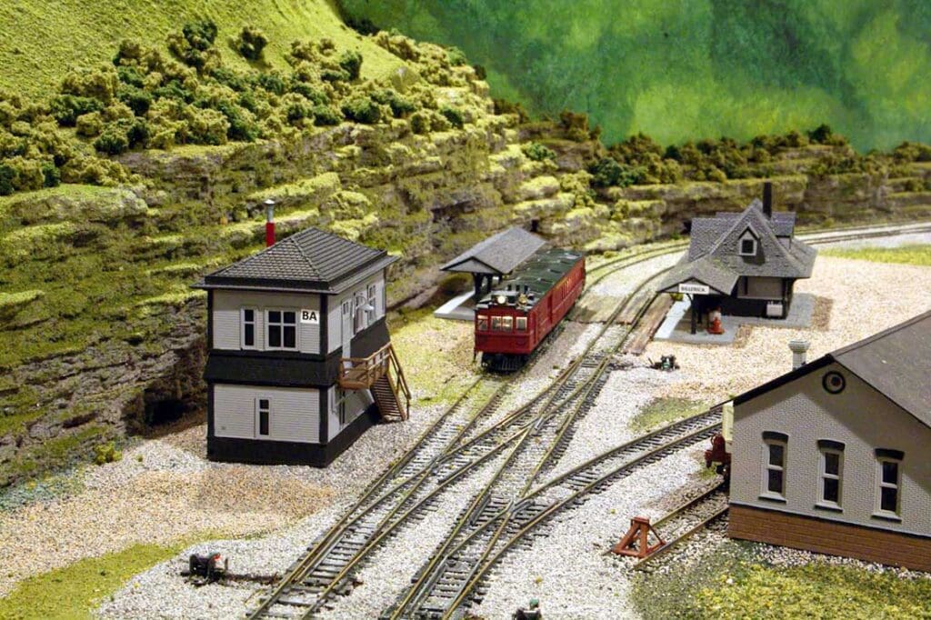 HO scale switcher layout with a central tower, rail car on tracks, and detailed town scenery depicting B&M railroad history.