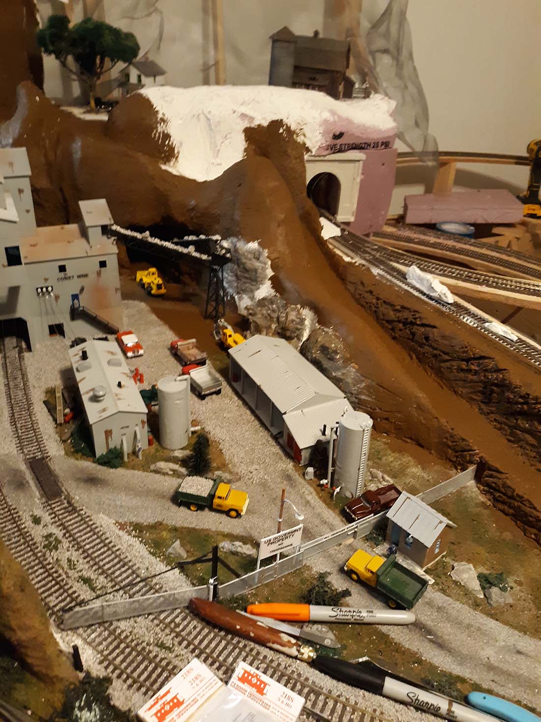 Model railroad benchwork with legs being levelled, the frame supported at working height in a basement