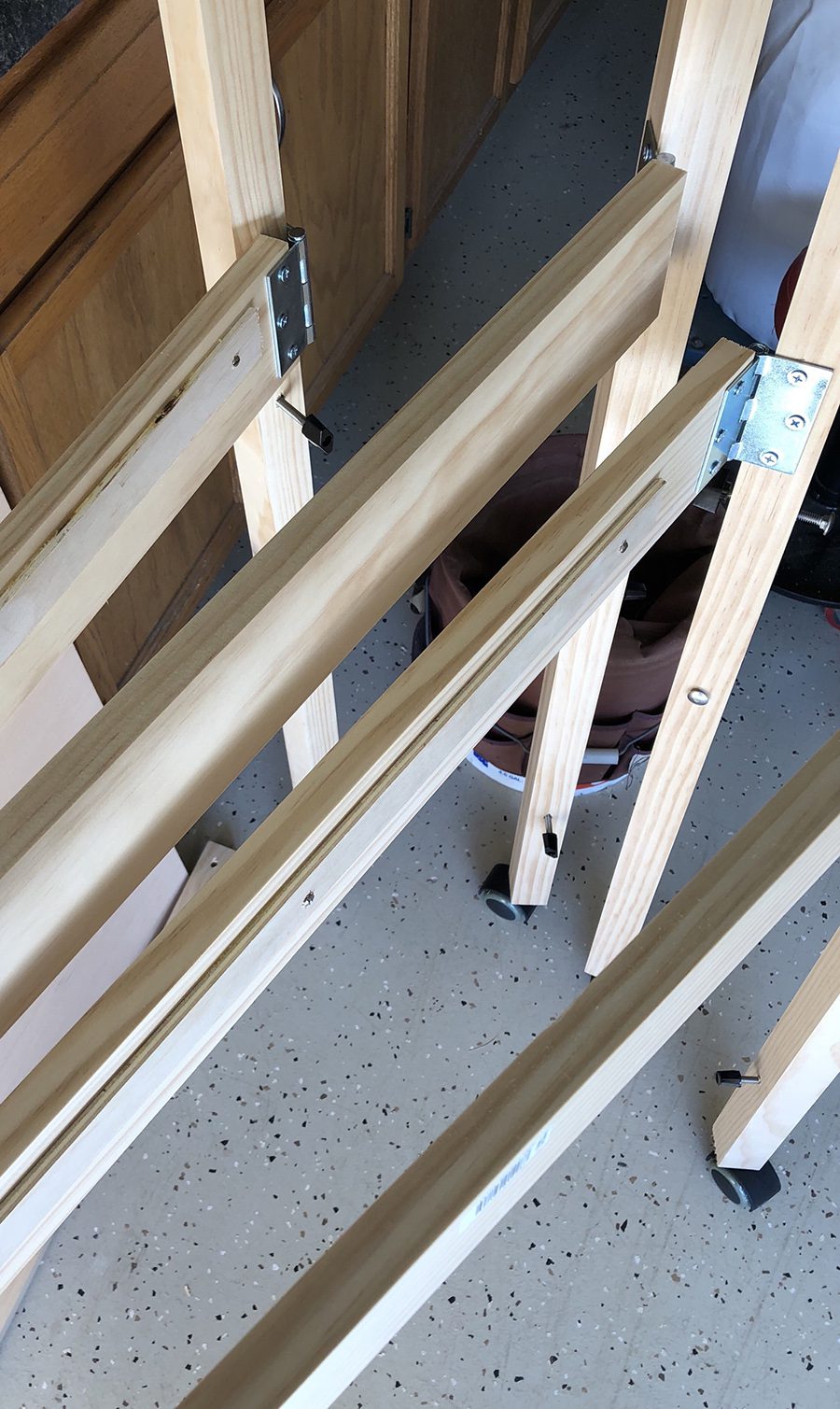 Folding legs on a model train bench hinged with steel butt hinges and fitted with castors