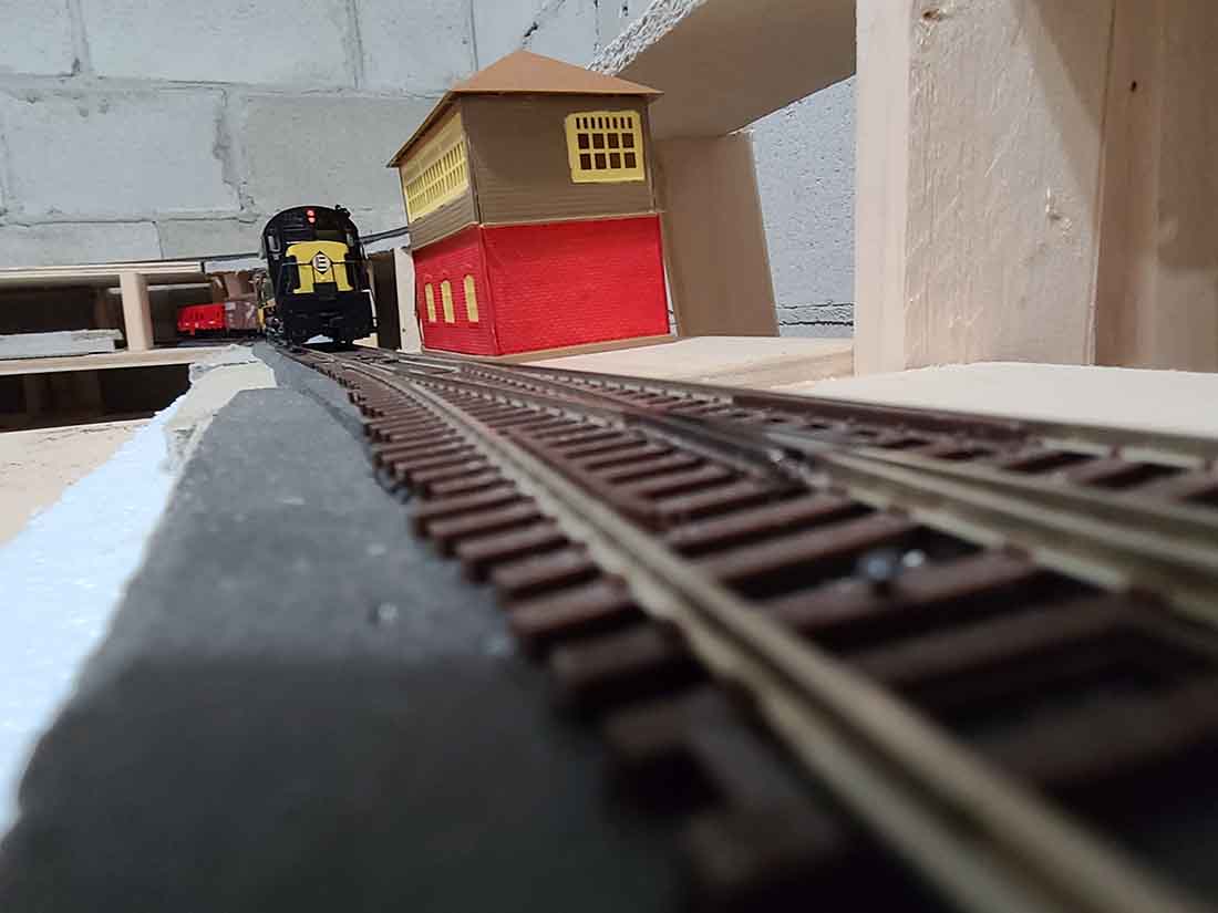 Finished HO scale model railroad on completed benchwork with mountain scenery and track in place