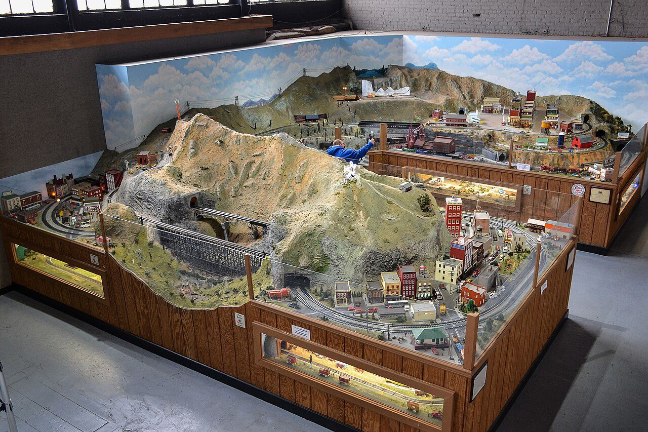 Large O gauge model railroad with a mountain, bridges and a town seen from above