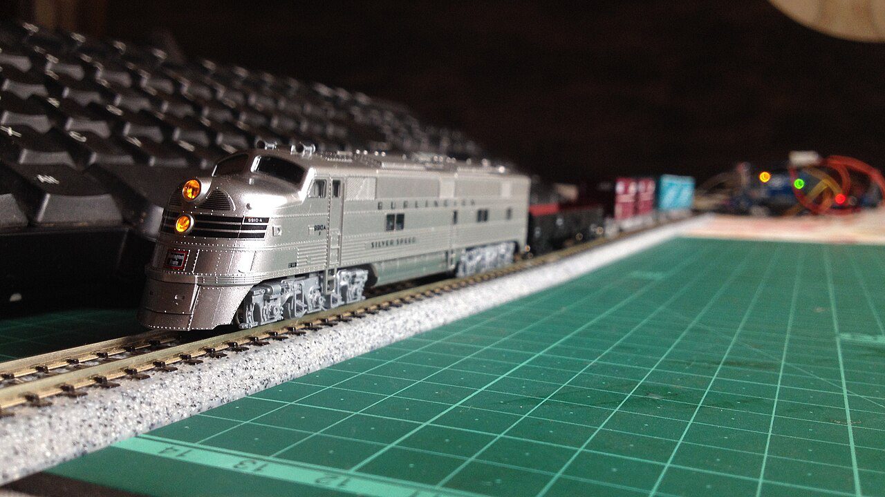 Silver streamlined Kato N scale diesel passenger locomotive with lit headlights on Unitrack